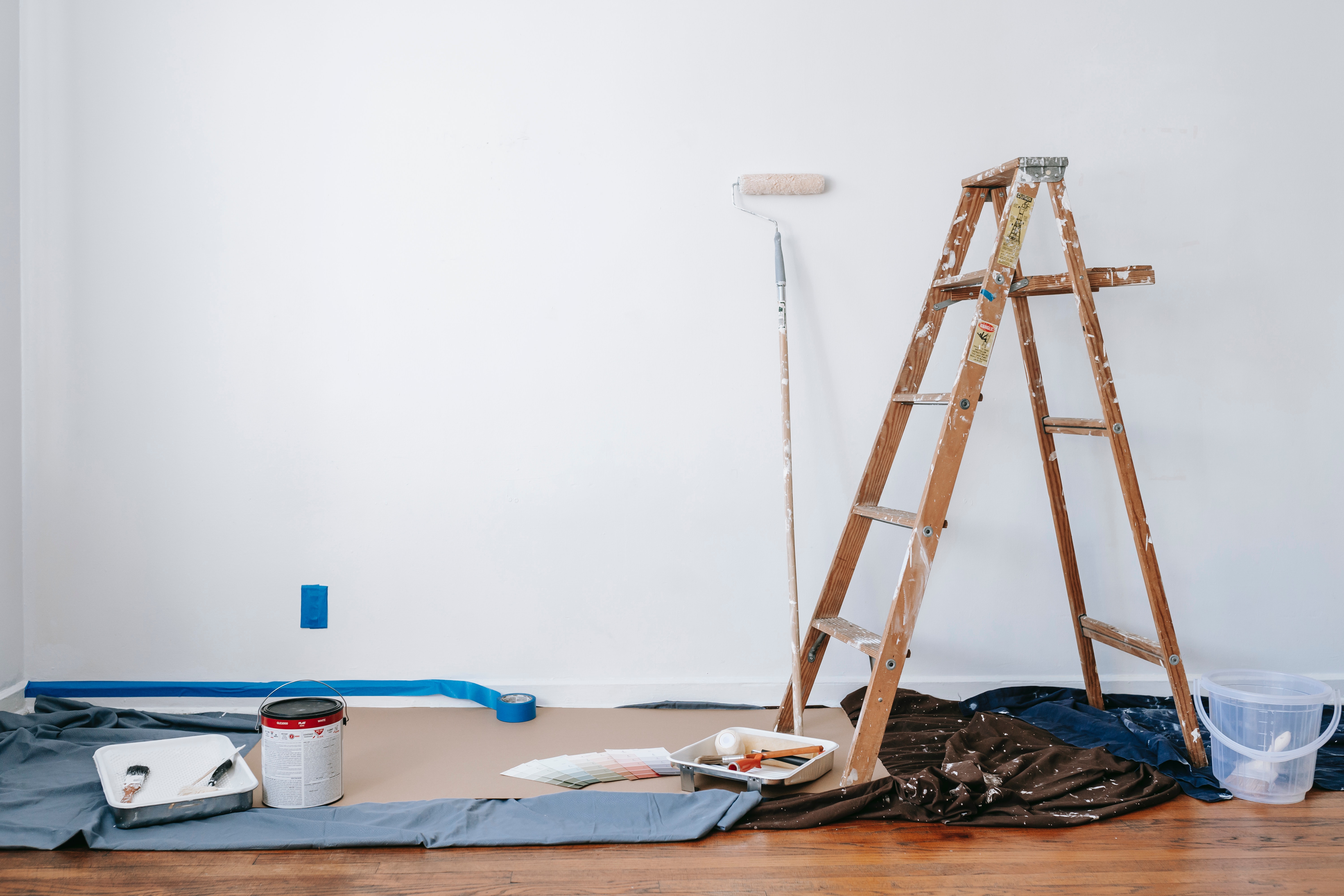Stock photo of living room with wall-paint, ladder, paint supplies scattered.